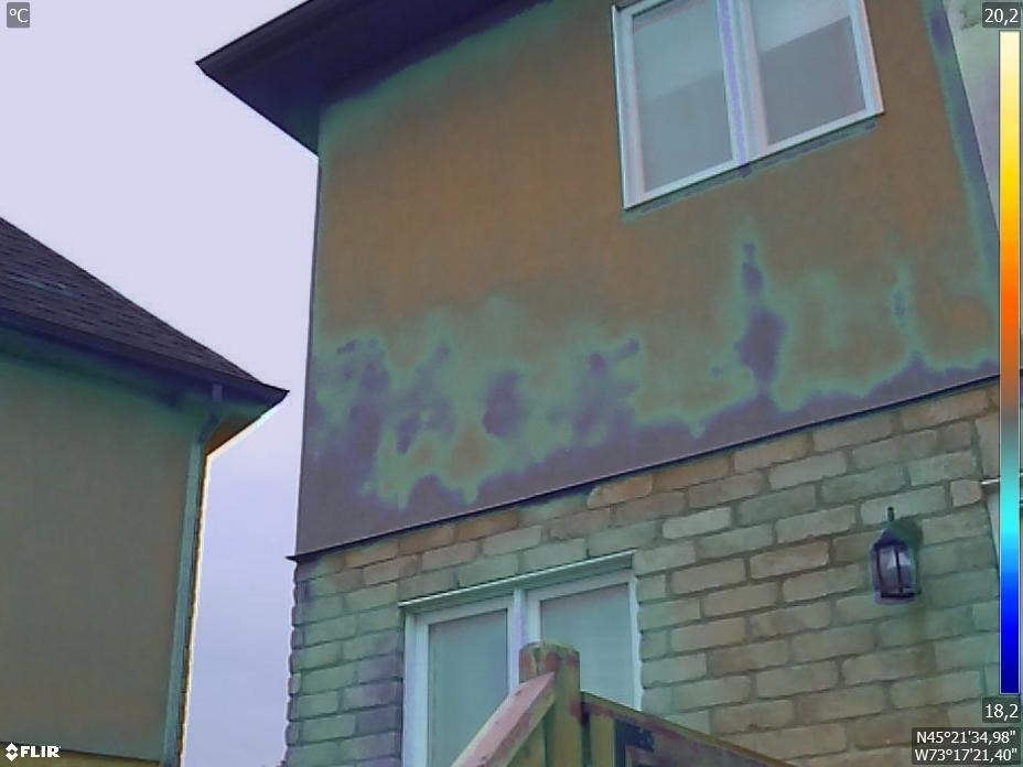 Image thermique d'un mur extérieur en stucco montrant des zones froides d'humidité au-dessus de la maçonnerie